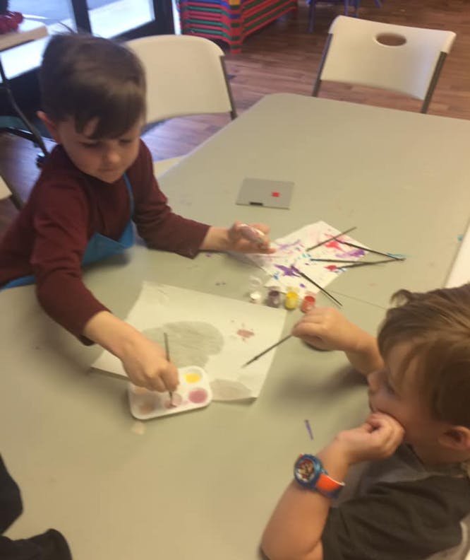 Two children painting at a table