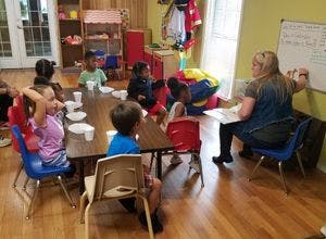Adult and children at tables in a classroom