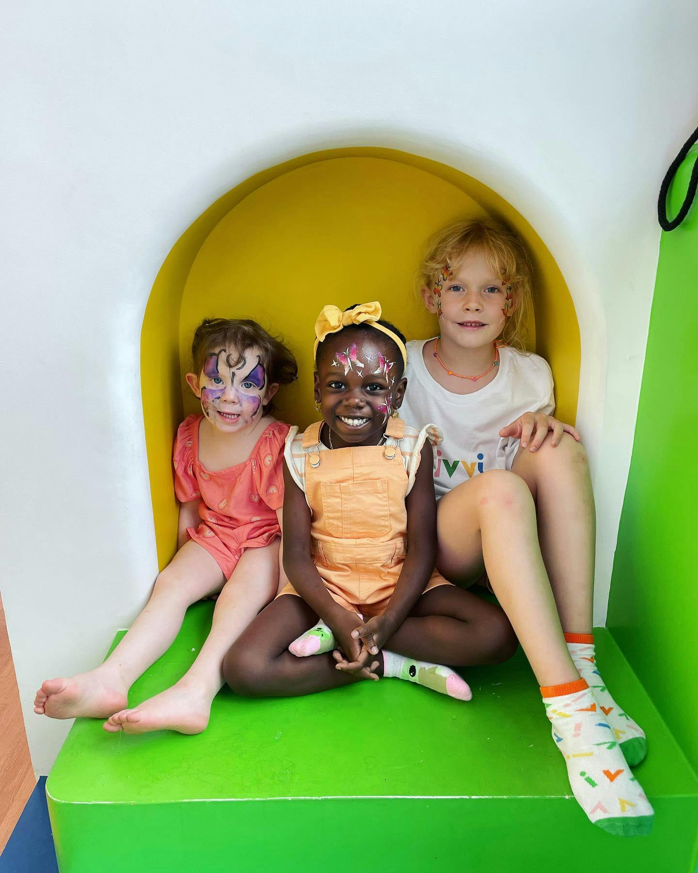 Three children with face paint sitting together