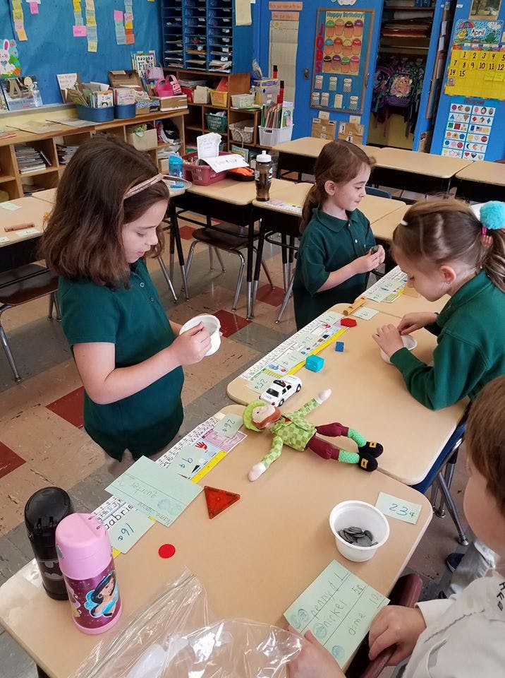 Children playing with toys and learning materials at desks in a classroom