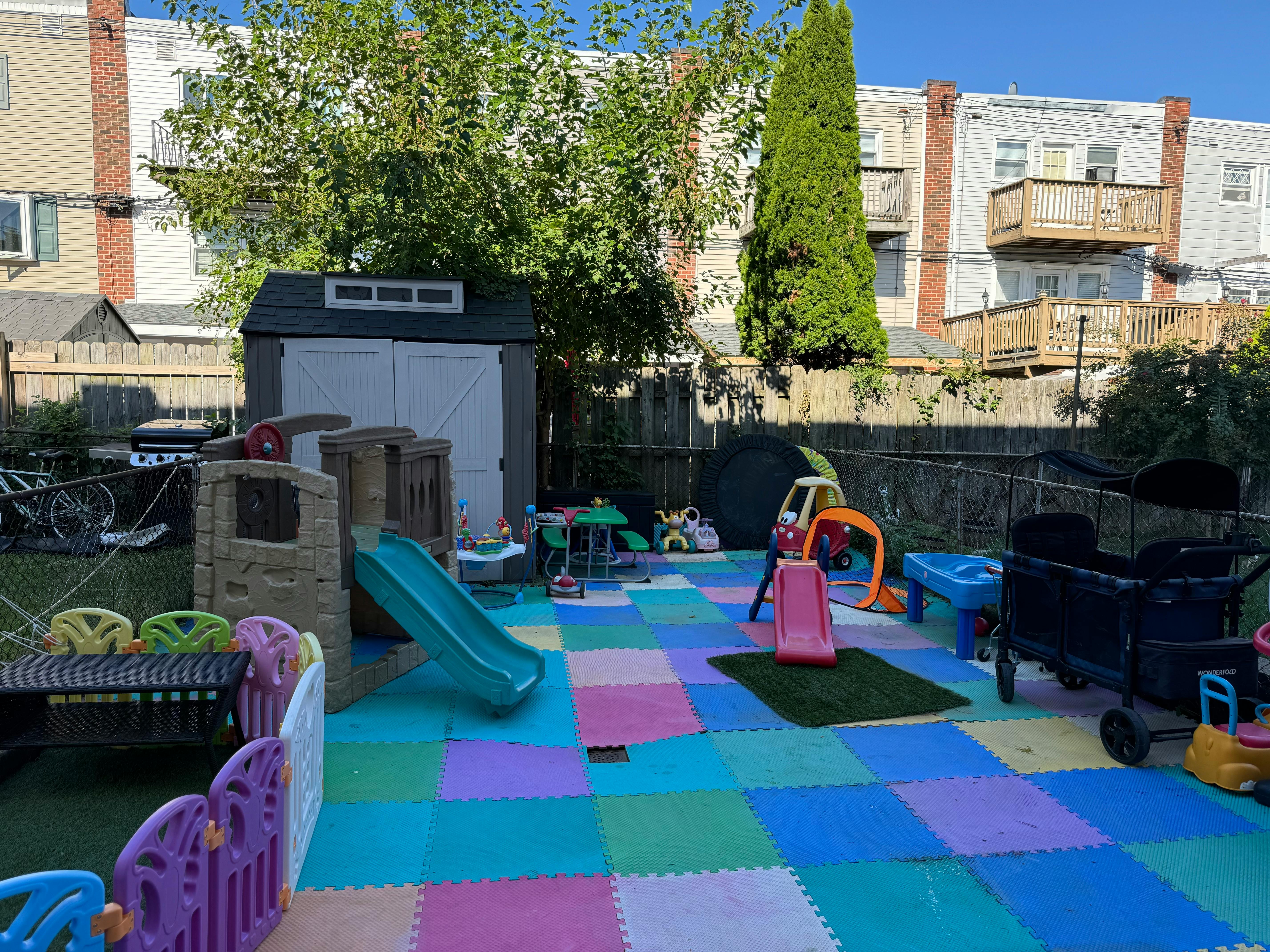 Outdoor play area with colorful interlocking foam tiles and various play equipment
