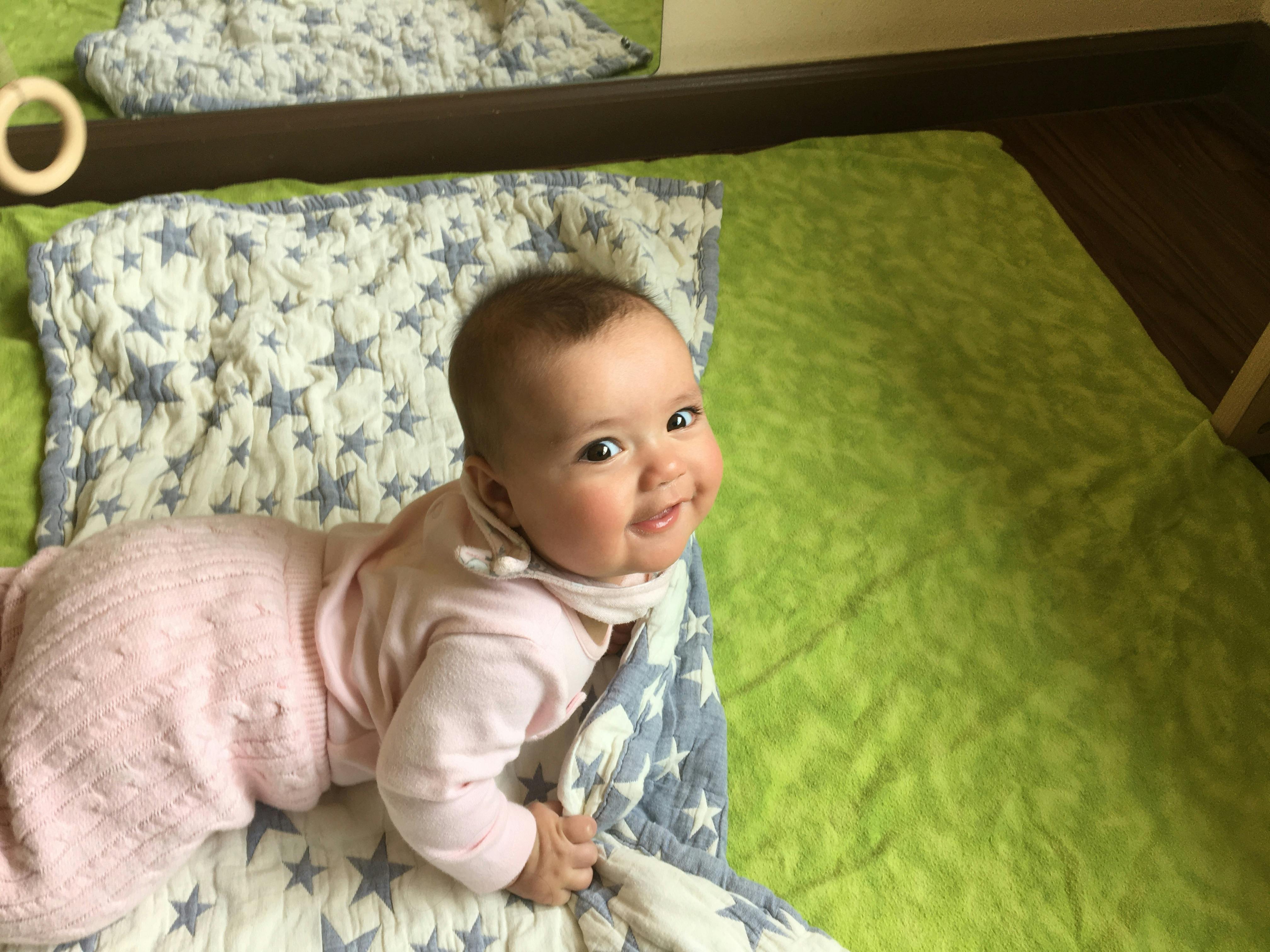 Child in pink clothing lying on a quilted blanket with blue and white stars