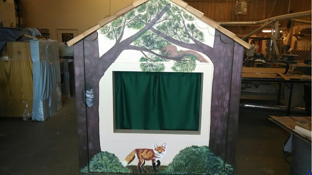 Puppet theater with painted trees, fox, and green curtains