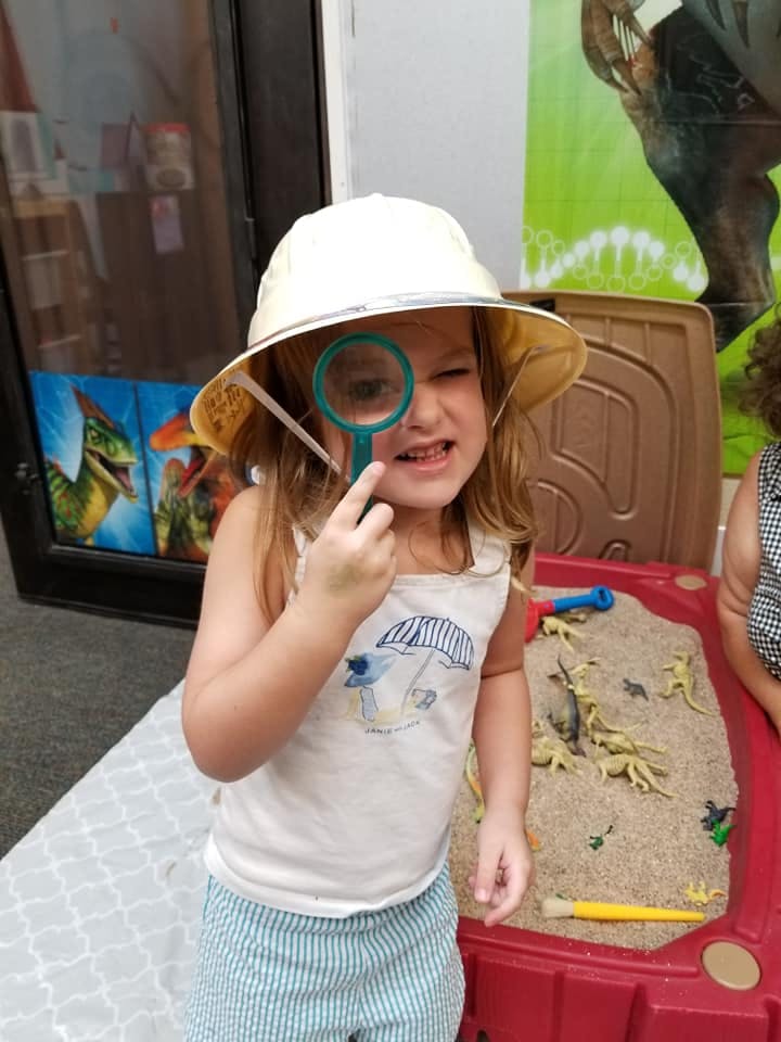 Child in a hat looking through a magnifying glass