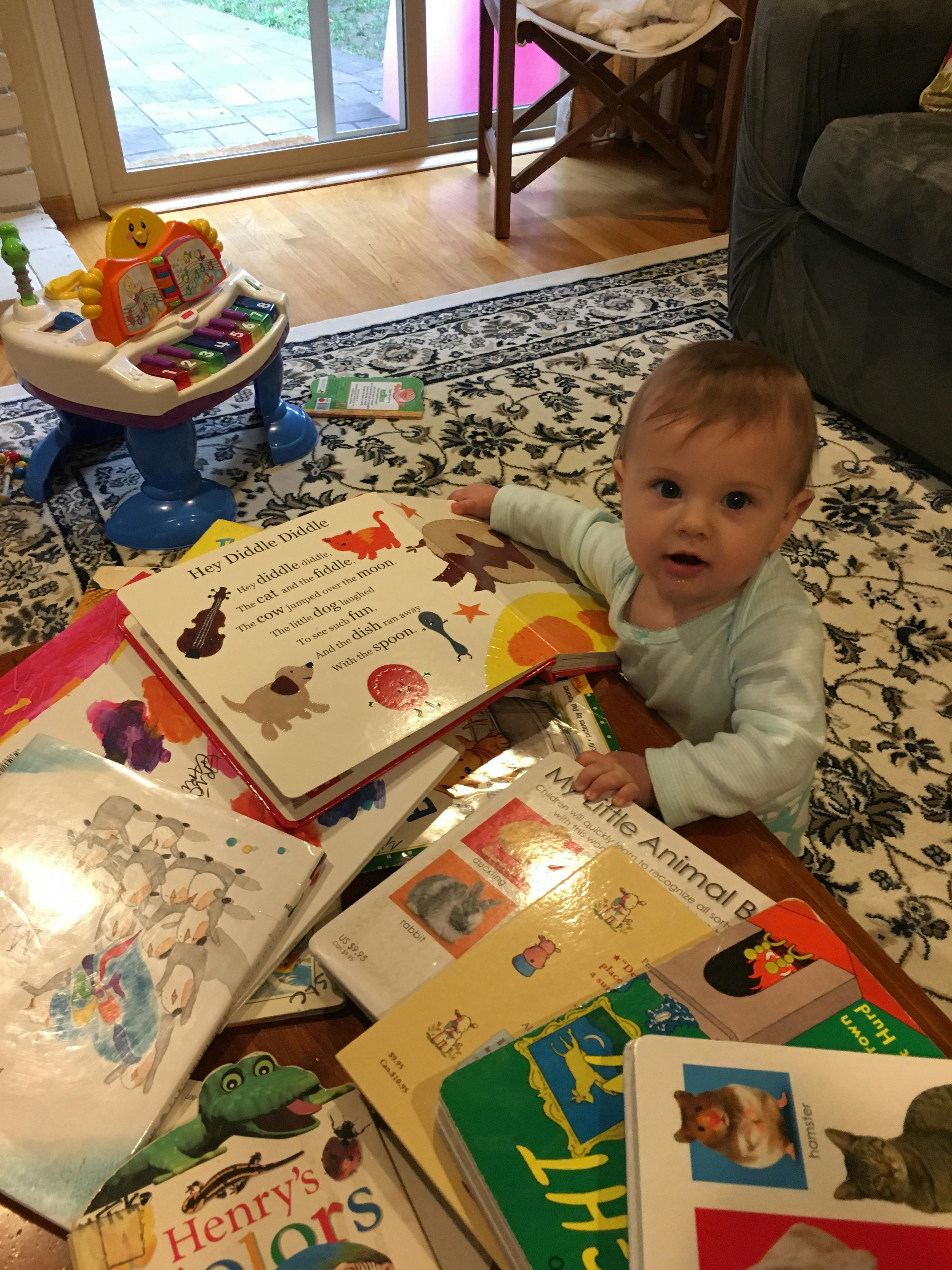 Child sitting on a rug surrounded by open books
