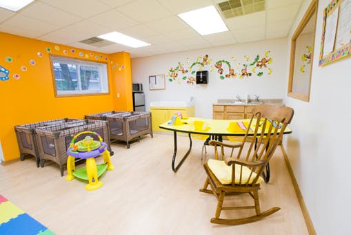 Nursery room with cribs, a baby walker, and a small table with chairs