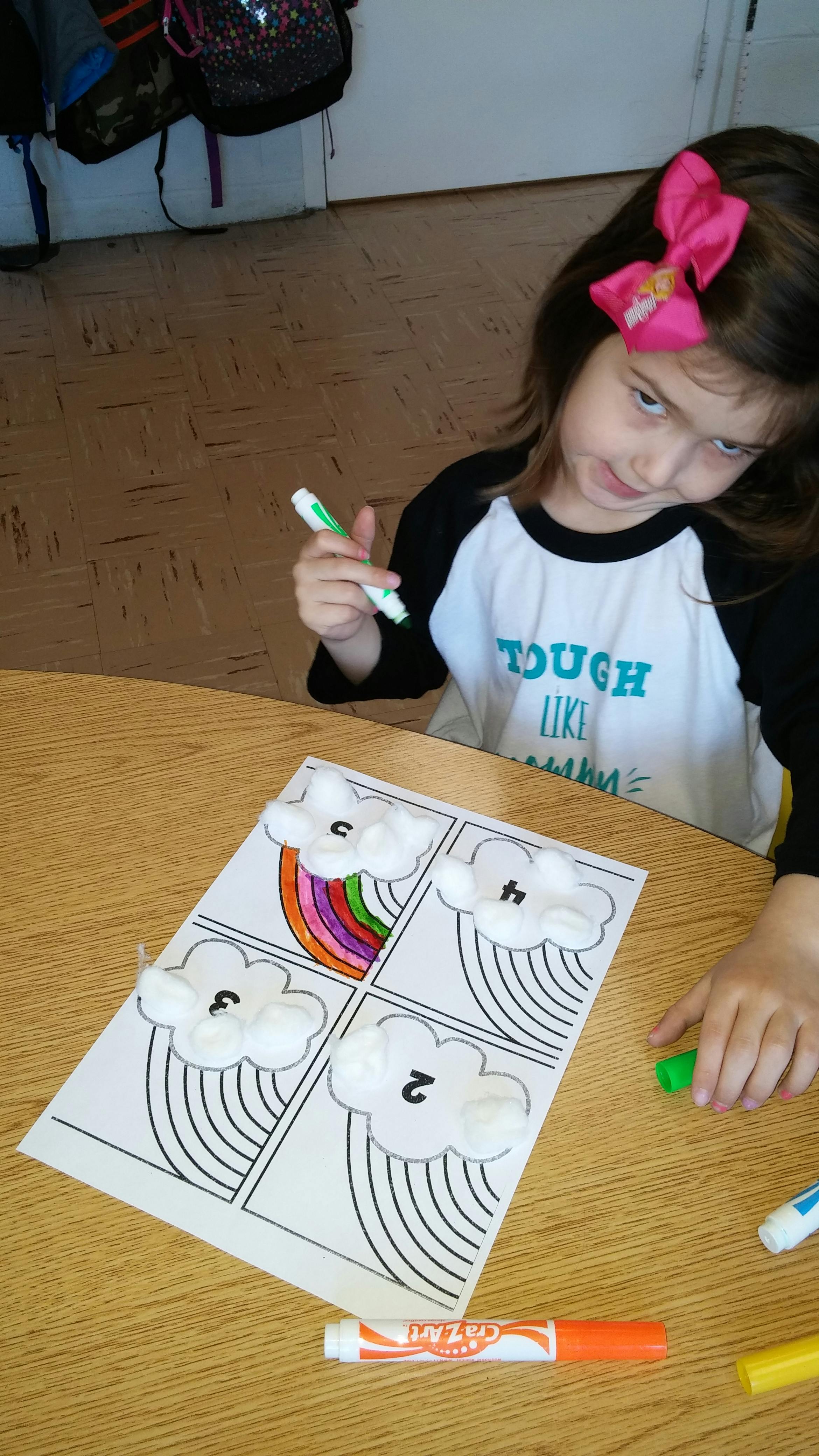 Child coloring a rainbow craft with markers