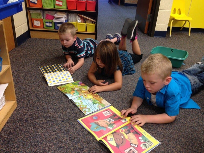 Three children lying on the floor reading books