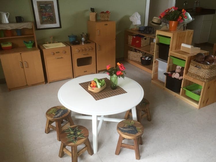 Playroom with small table and chairs, toy kitchen, and shelves with shelves