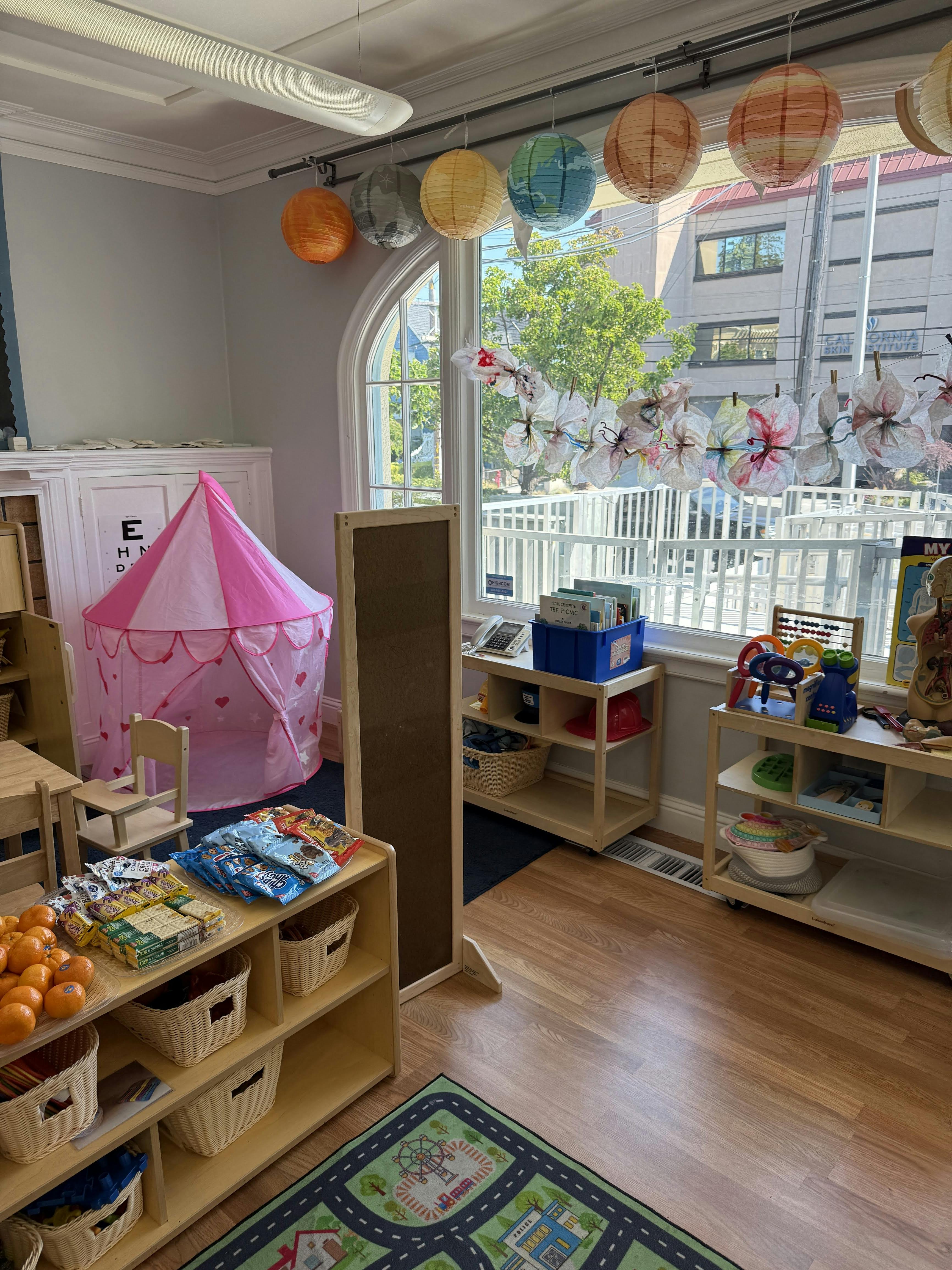 Playroom with a pink tent, shelves of toys, and a rug with a road map rug