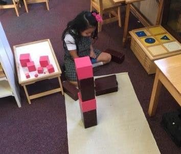 Child playing with pink and brown blocks on a mat