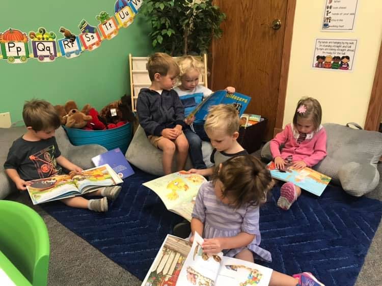 Children sitting on the floor reading books in a classroom