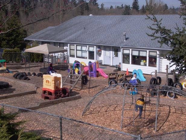 Child on a climbing dome in a playground with a building in the background