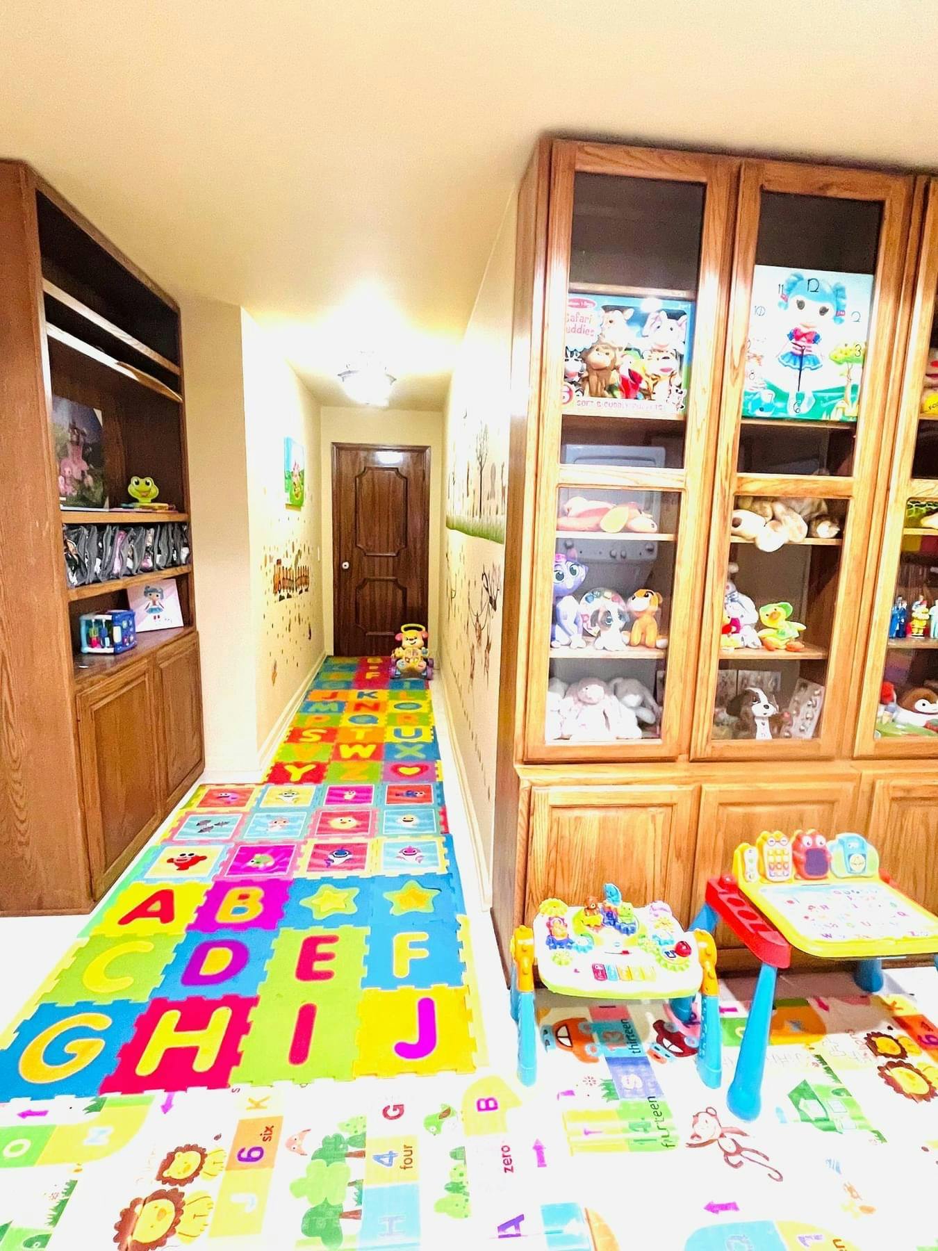Hallway with alphabet play mats and wooden cabinets filled with toys