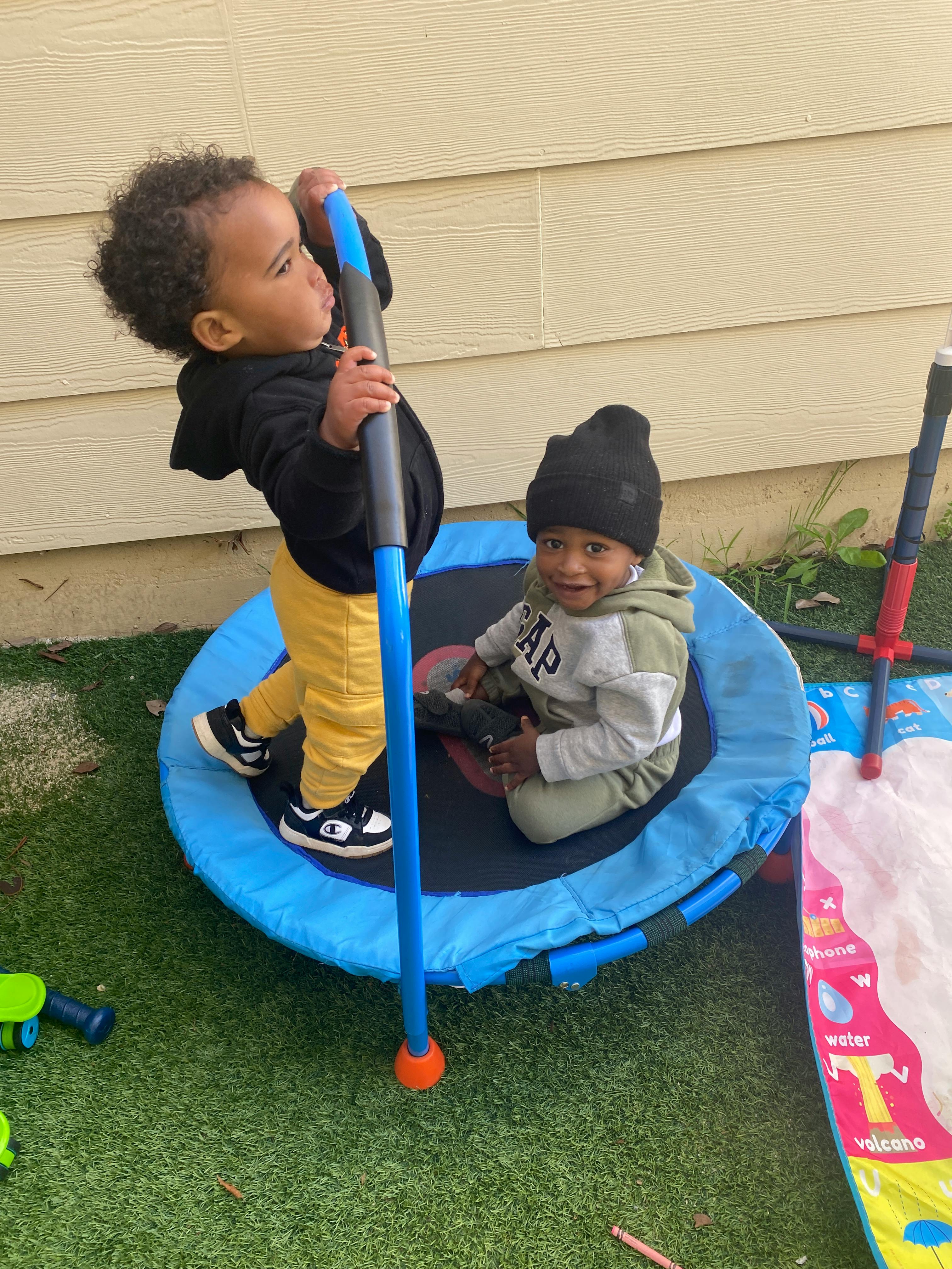 Two children playing on a small trampoline