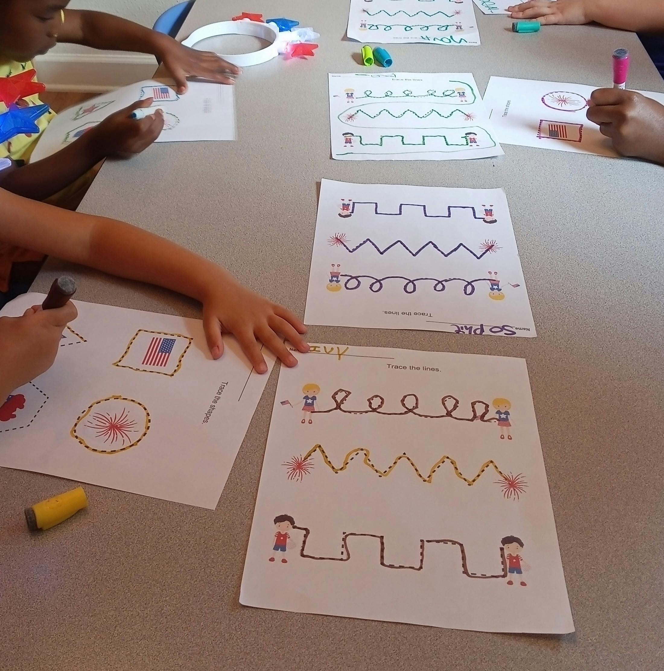 Children tracing lines and shapes on papers with markers