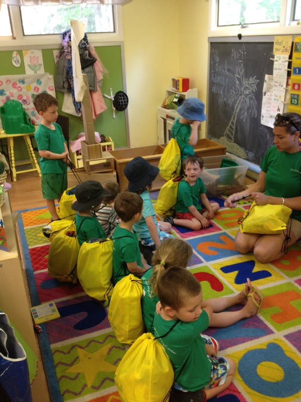 Adult and children sitting on a colorful rug in a classroom