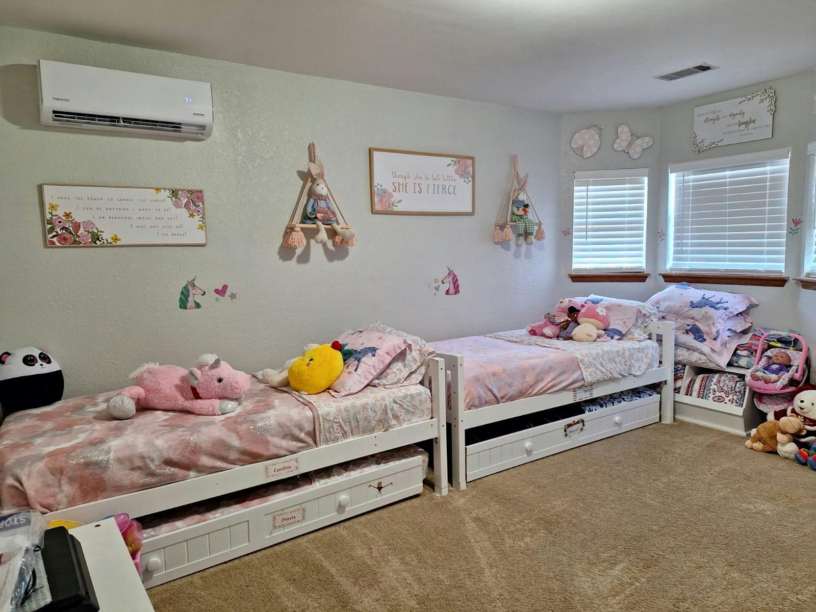 Two beds with pink bedding and stuffed animals in a room