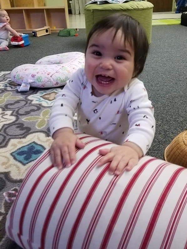 Child on hands and knees over a striped pillow