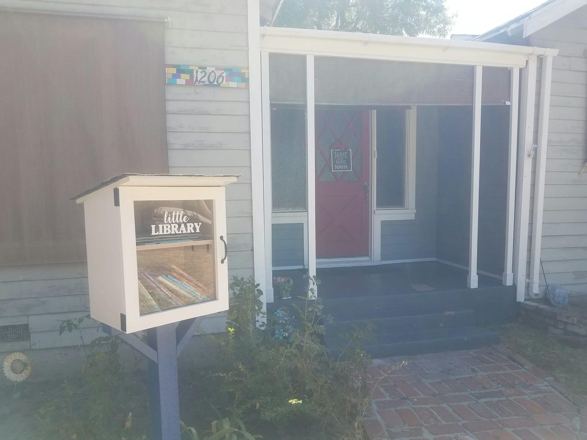 Little Free Library box with "Little Library" text in front of a house