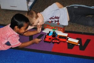 Two children playing with a toy train