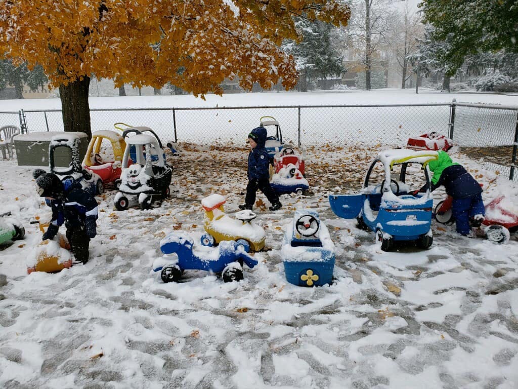 Children playing in snow with ride-on toys