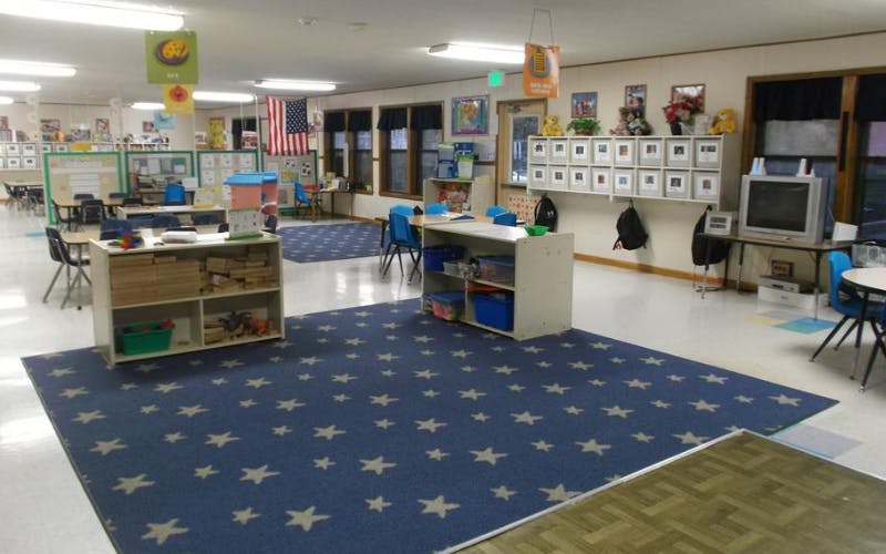 Classroom with tables, chairs, and play areas with a blue star-patterned rug