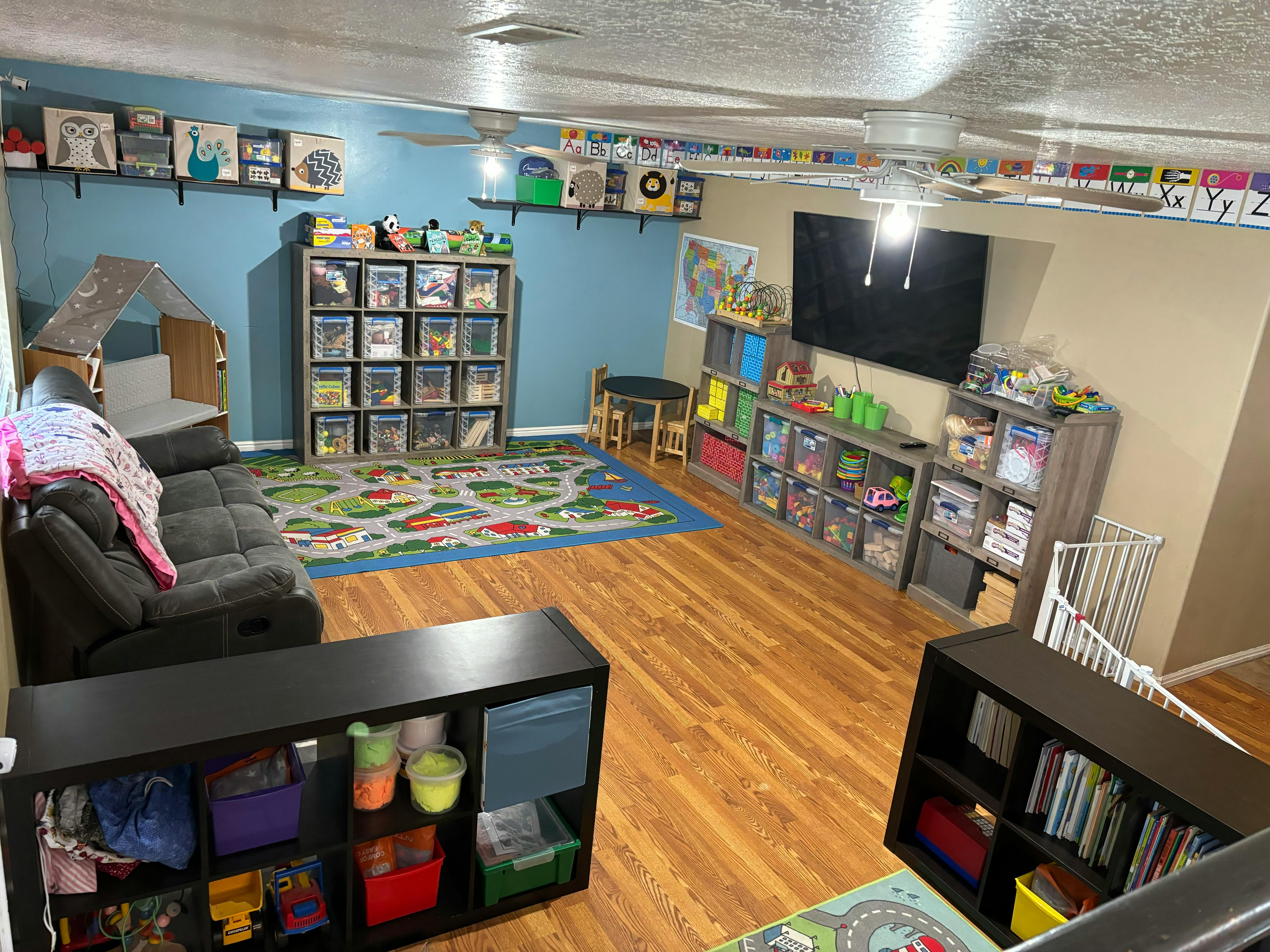 Playroom with a sofa, toy storage, and a rug with a road design