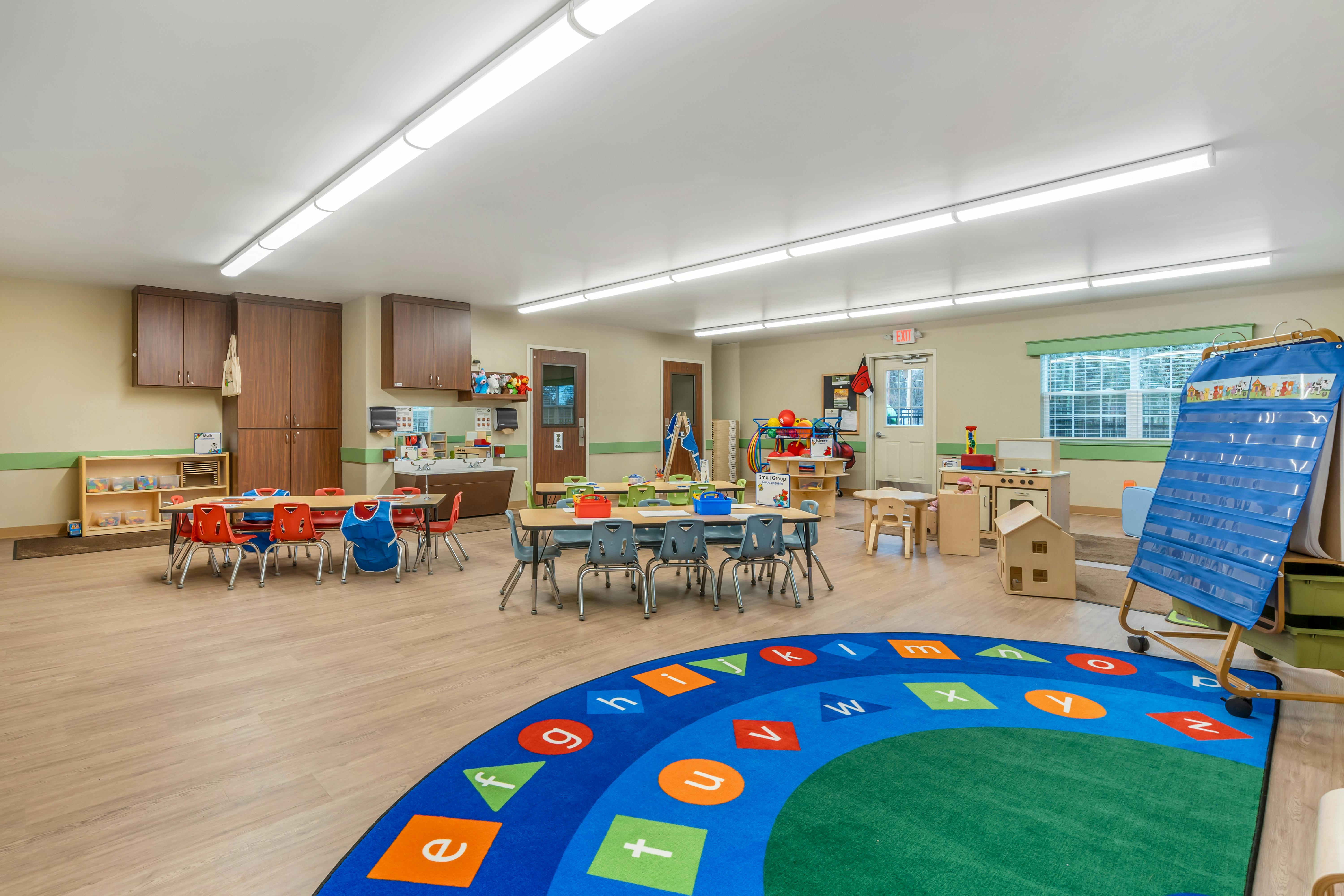 An empty early childhood classroom with multiple tables and chairs
