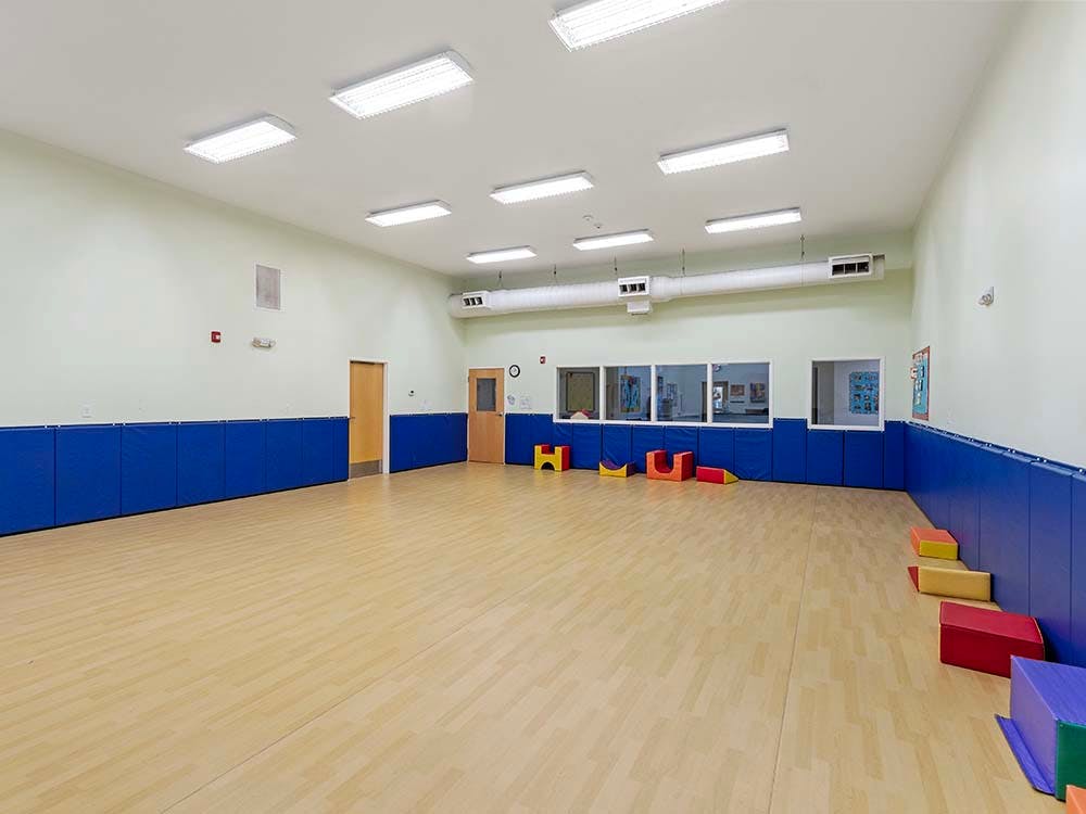 Empty indoor play area with blue padded walls and soft play shapes