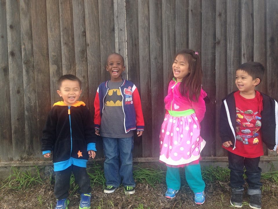 Four children standing in front of a wooden fence