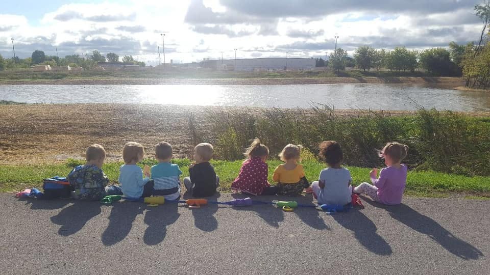 Children sitting on the ground looking at a body of water