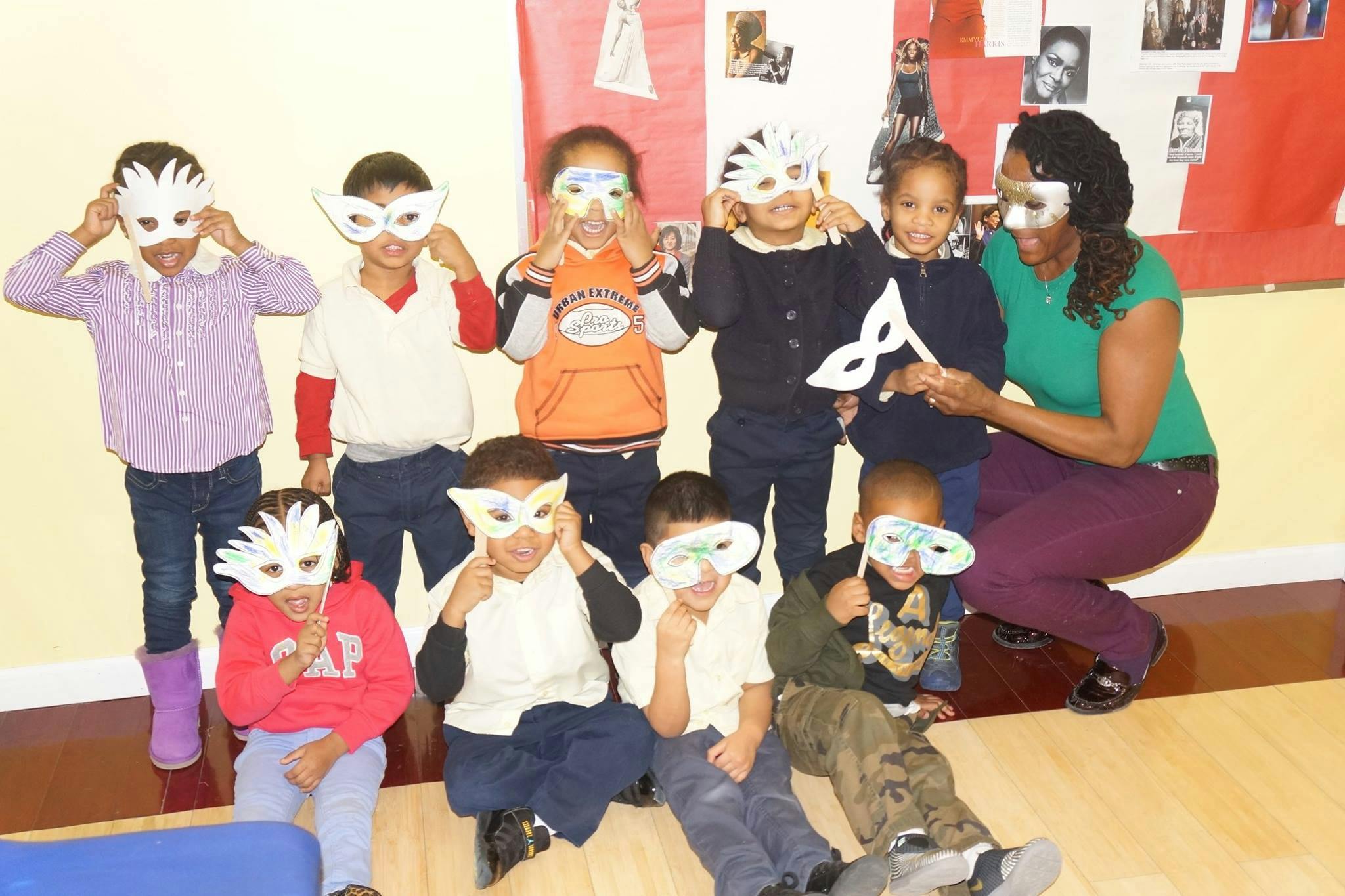 Adult and children holding white masks to their faces