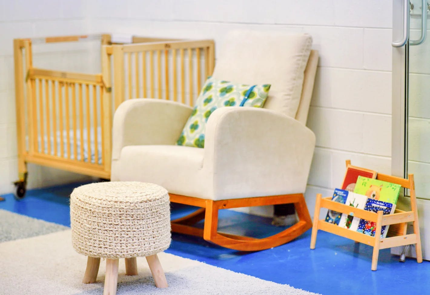 Crib, rocking chair, and small bookshelf with books in a room