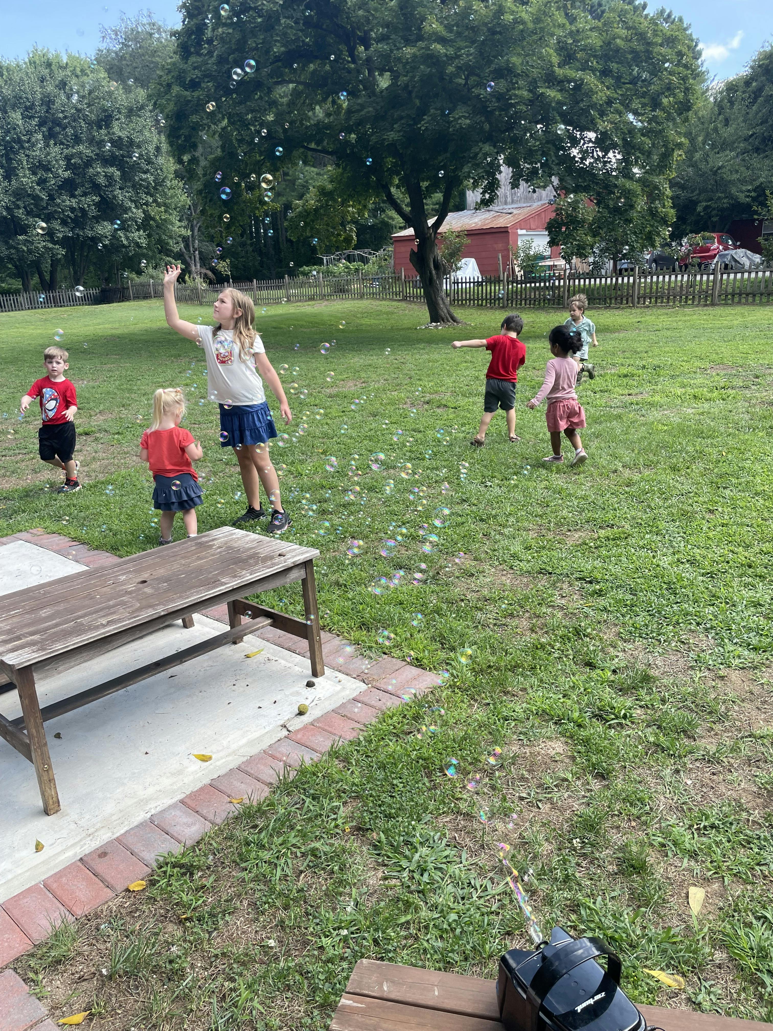 Children playing with bubbles in a grassy yard