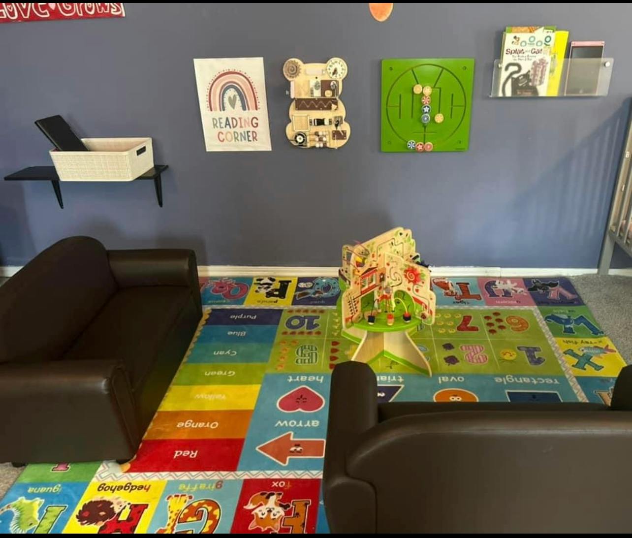 Children's play area with colorful rug, small sofas, and wall decorations