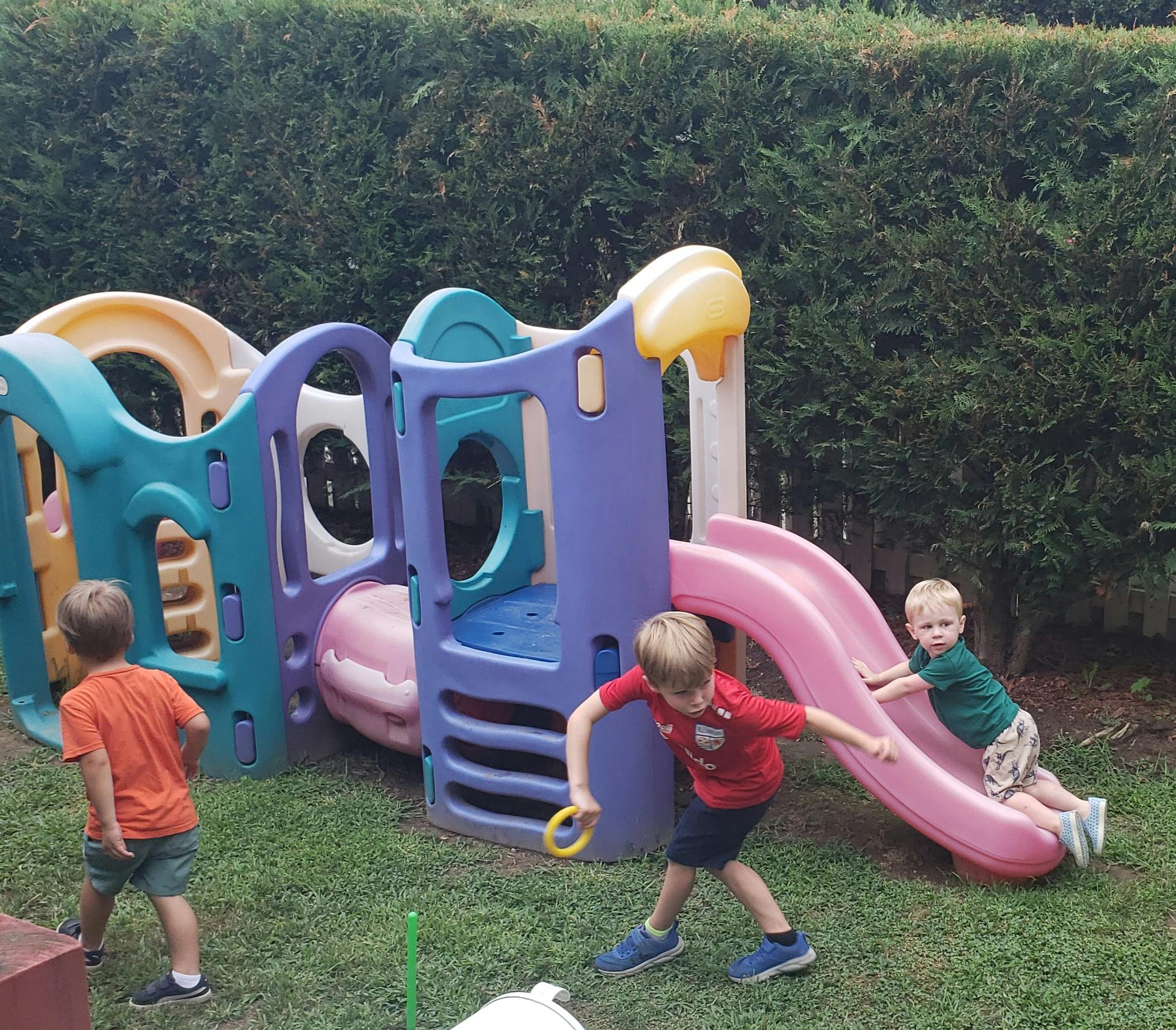 Three children playing on a colorful playground structure