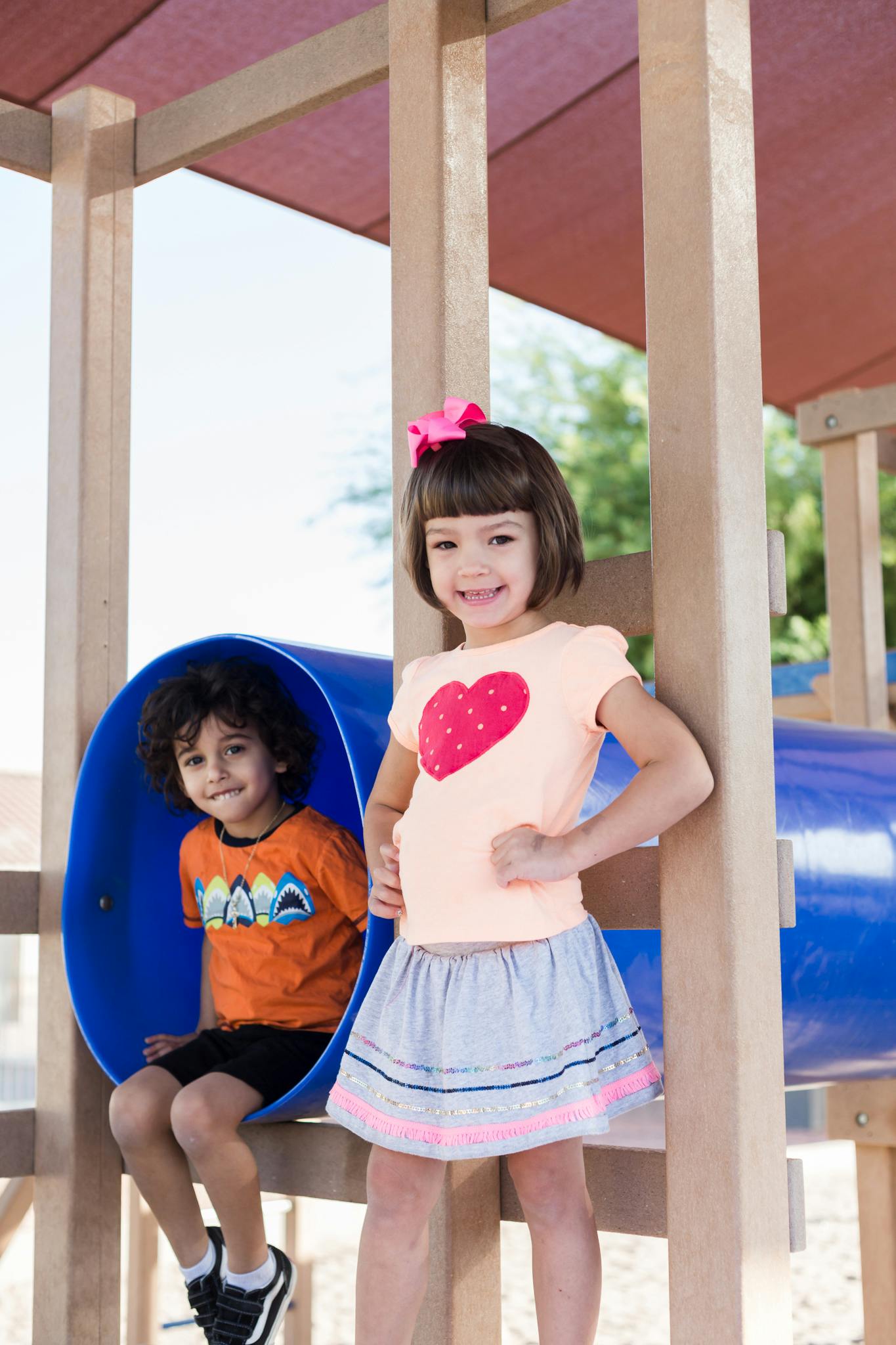 Two children on a playground structure, one in a blue tunnel