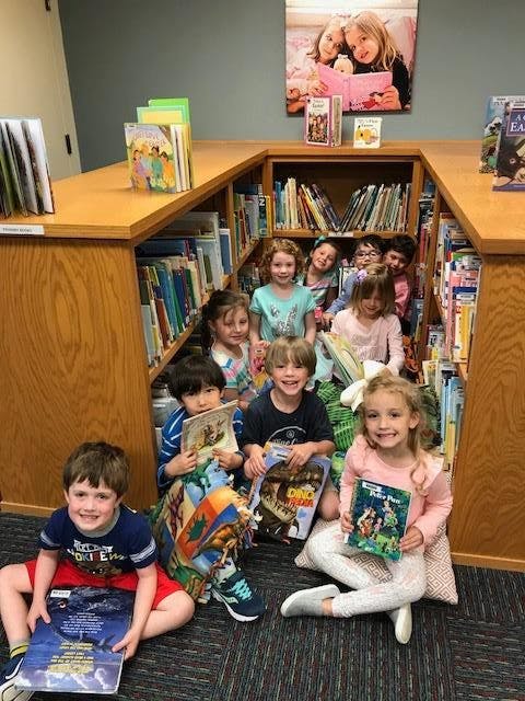Children sitting on the floor in a library with books