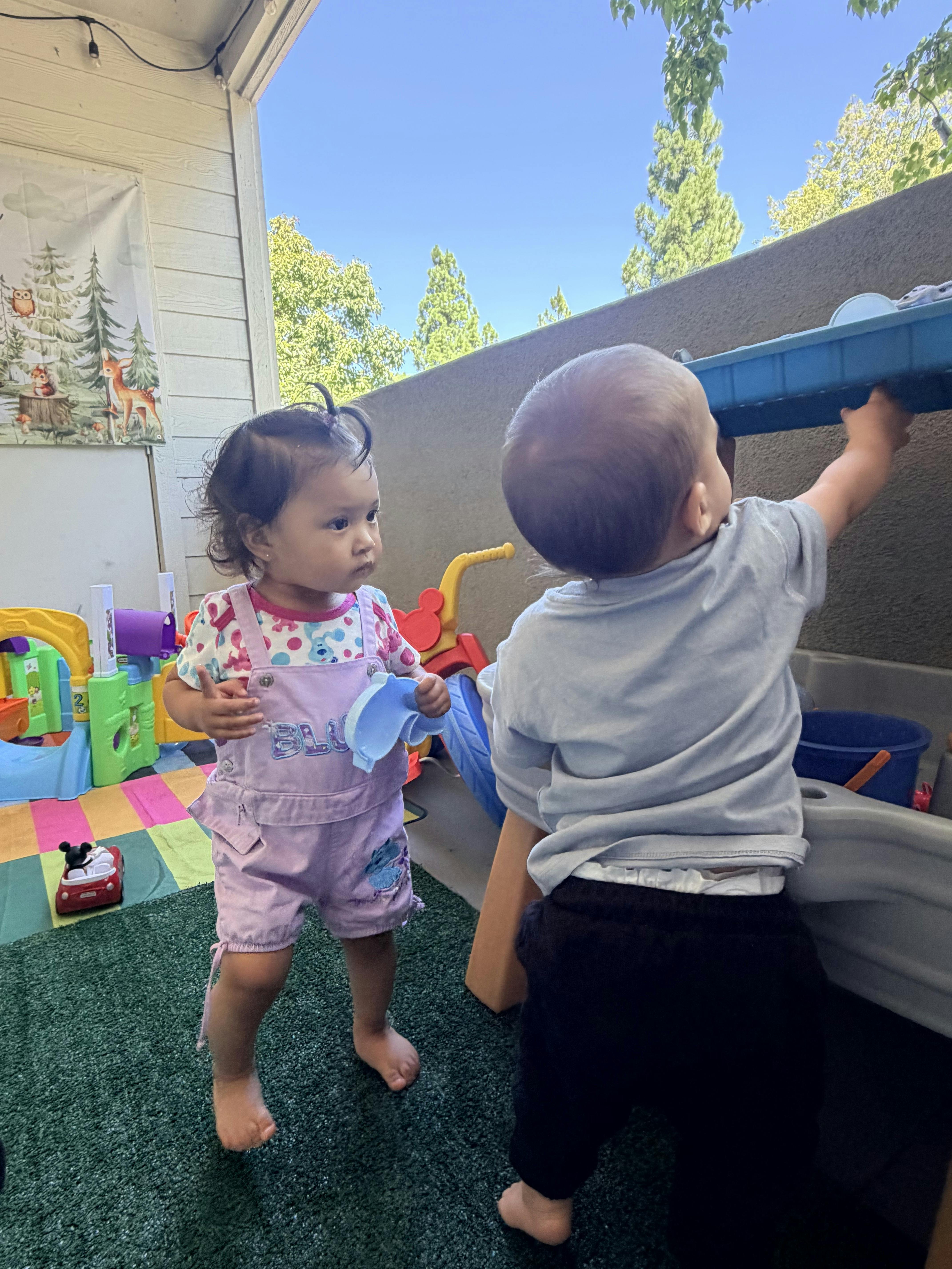 Two children playing with a water table on a patio