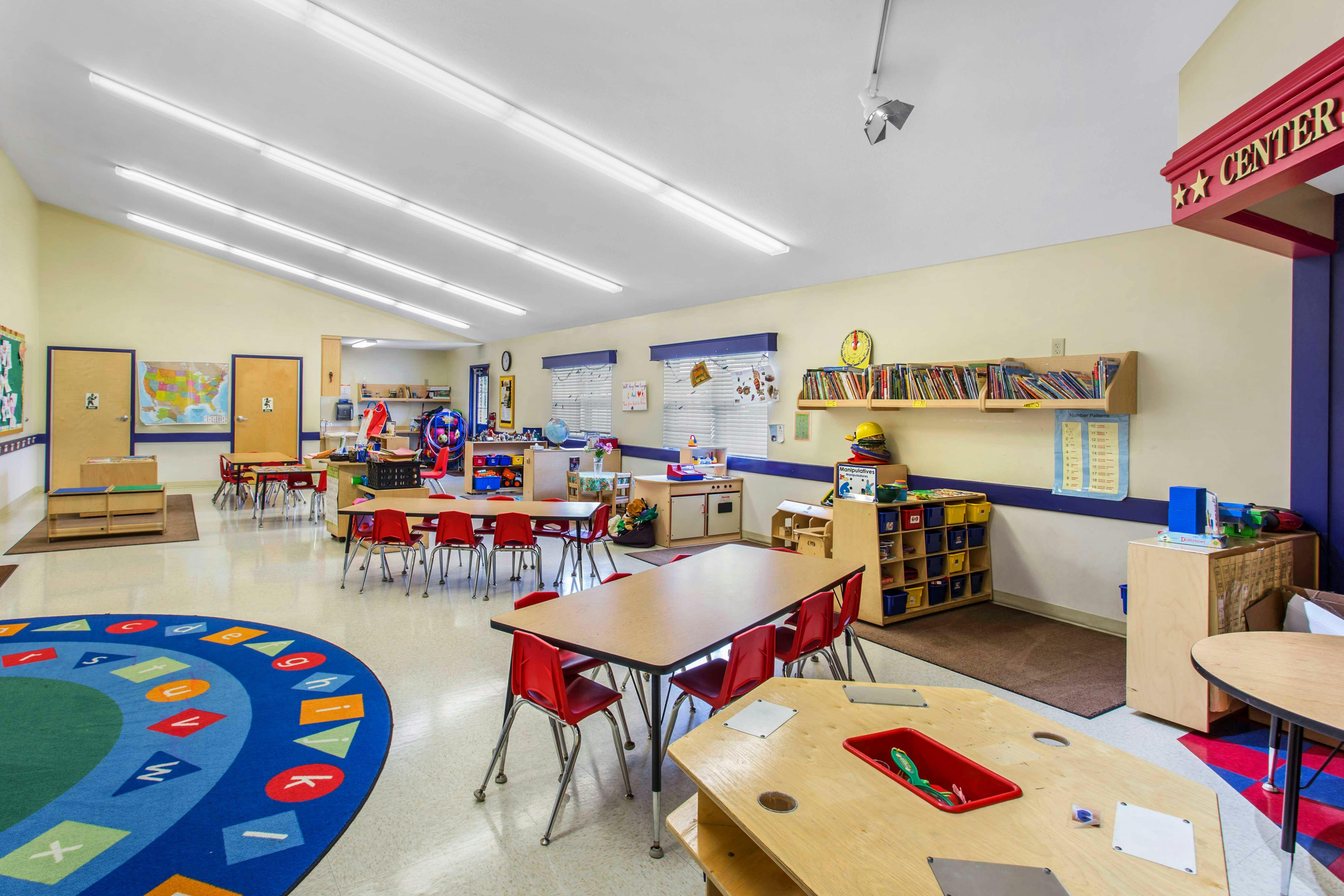 Classroom with tables, chairs, and a colorful rug