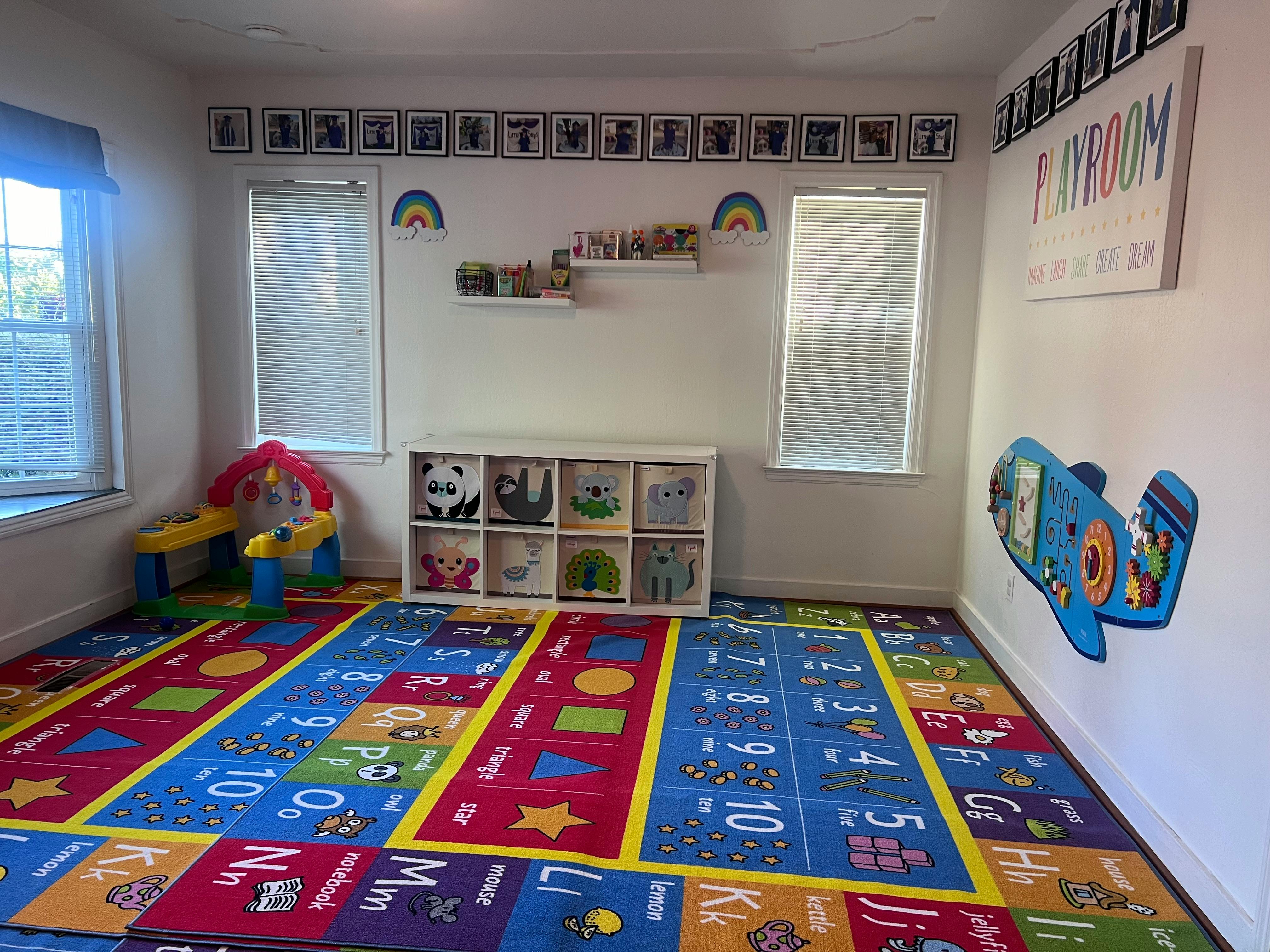Playroom with colorful alphabet and number rug, toy storage, and windows