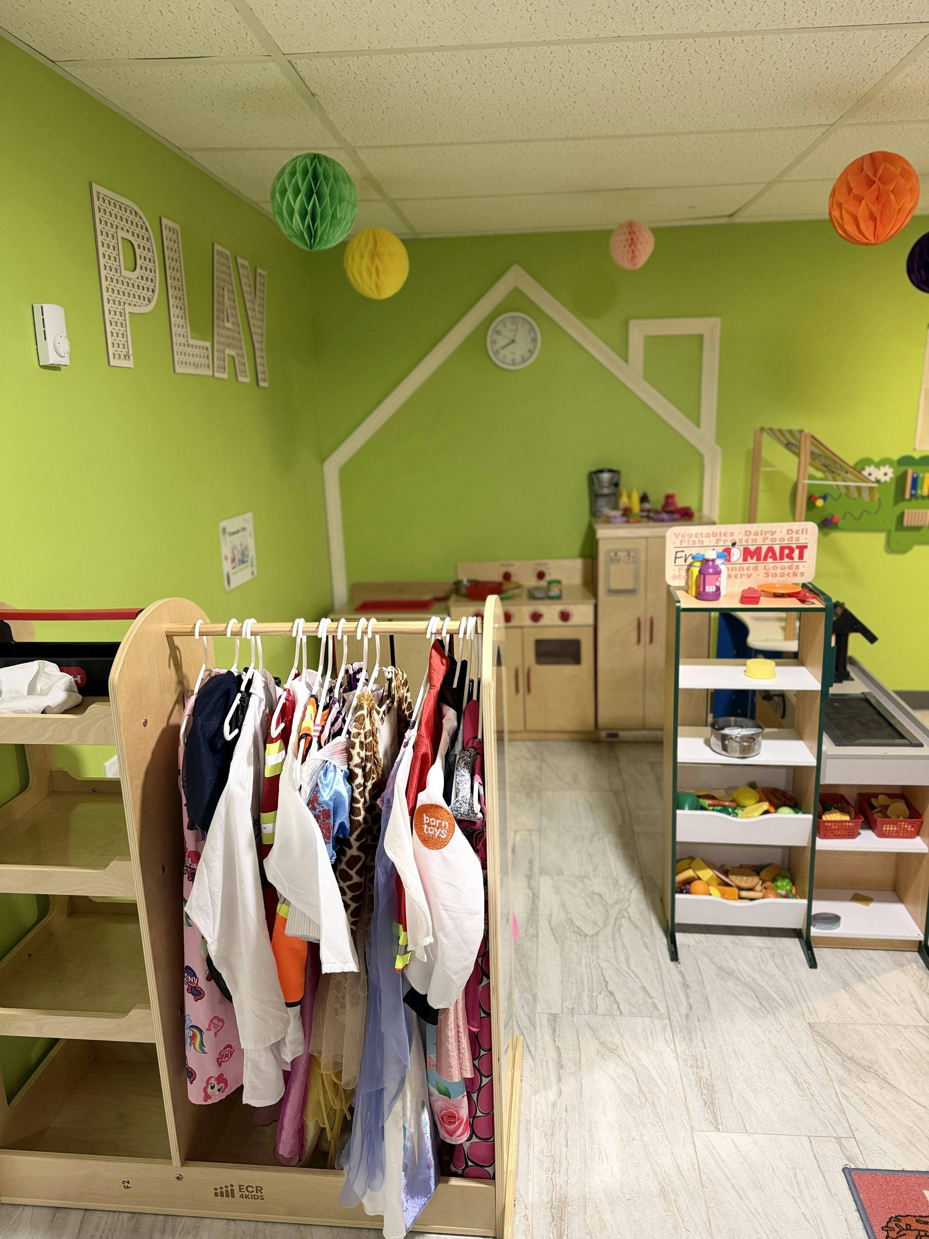 Playroom with a dress-up rack, toy kitchen, and grocery store setup