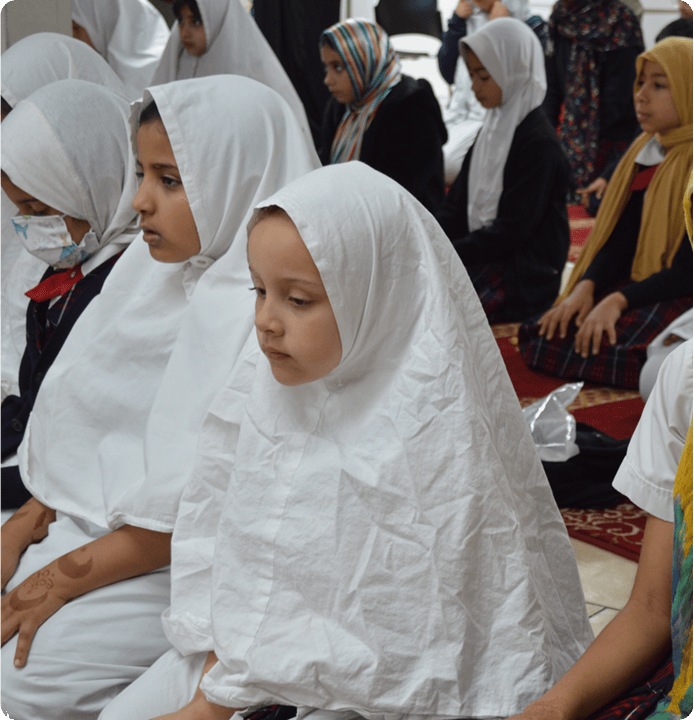 Group of children wearing hijabs, seated on the floor