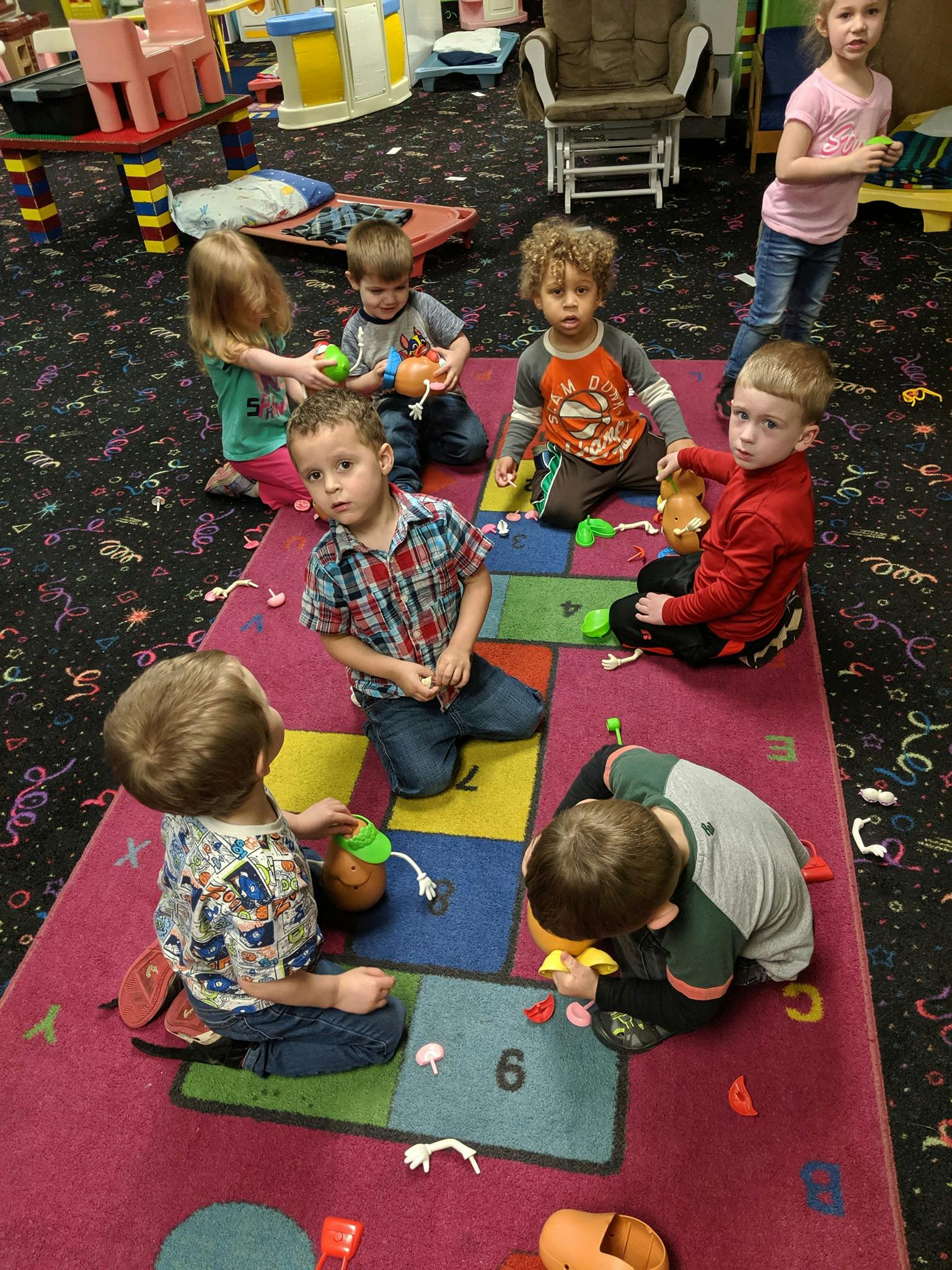 Children playing with toys on a colorful rug in a classroom