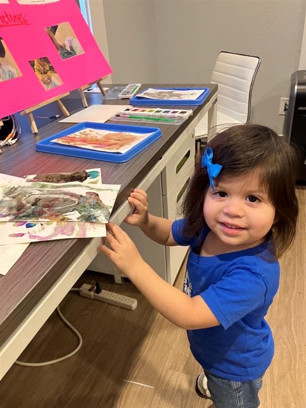 Child standing next to a table with art supplies