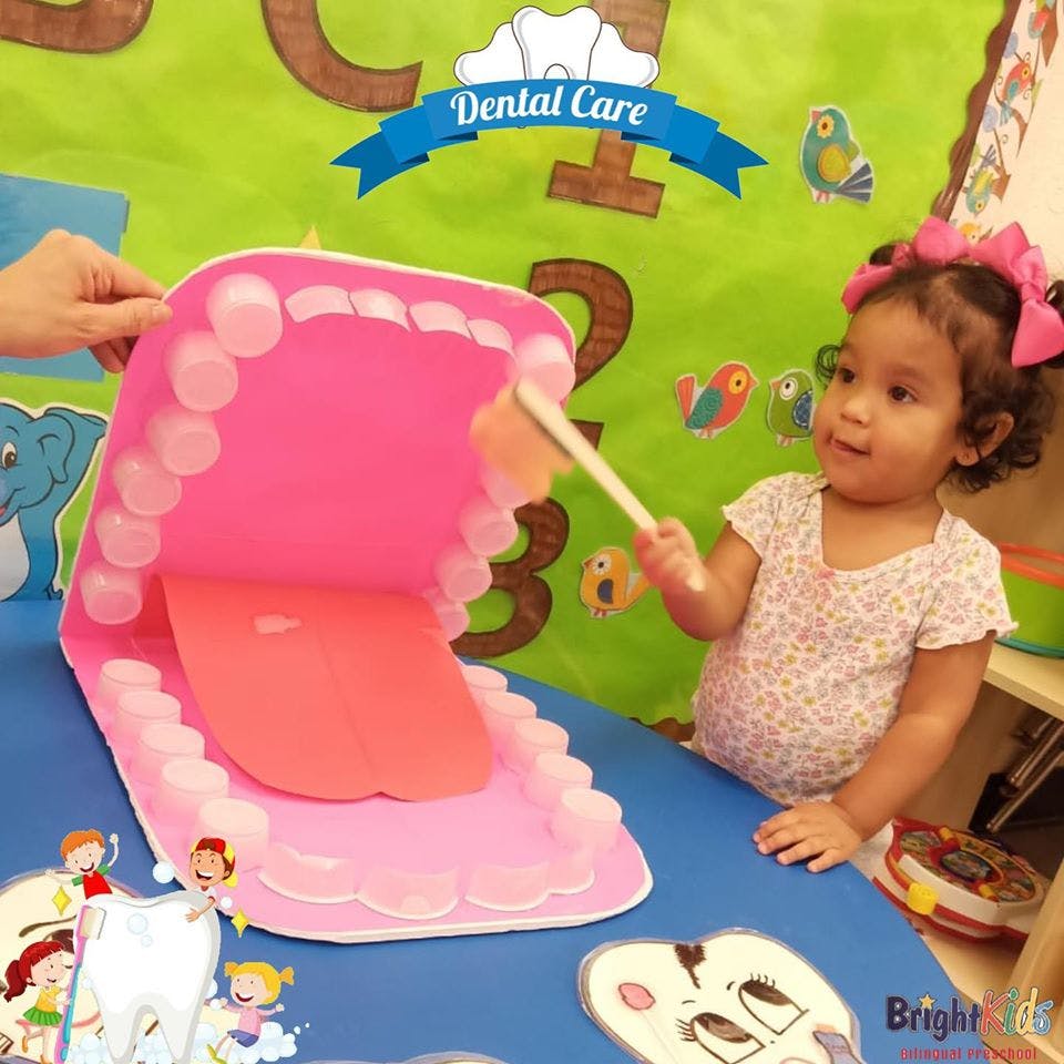 Child brushing a large model of teeth with a toothbrush