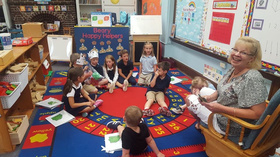 Adult and children sitting on a rug in a classroom