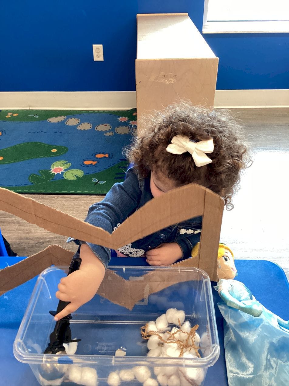 Child playing with a toy in a clear bin with cotton balls