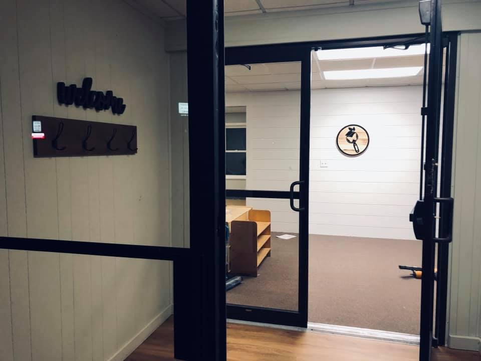 Open glass door leading into a room with a wooden shelf and a clock on the wall